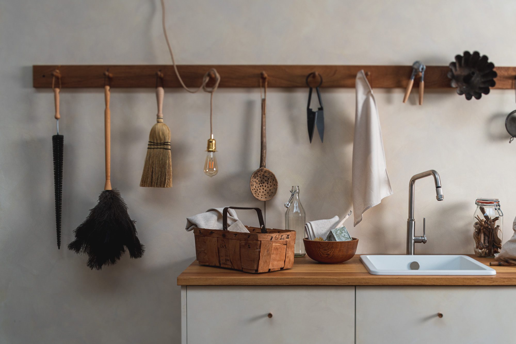 A detailed view of a bathroom basin with an array of cleaning brushes and other elements neatly arranged along it, skillfully photographed by Brett Charles for interior architecture photography in the UK.